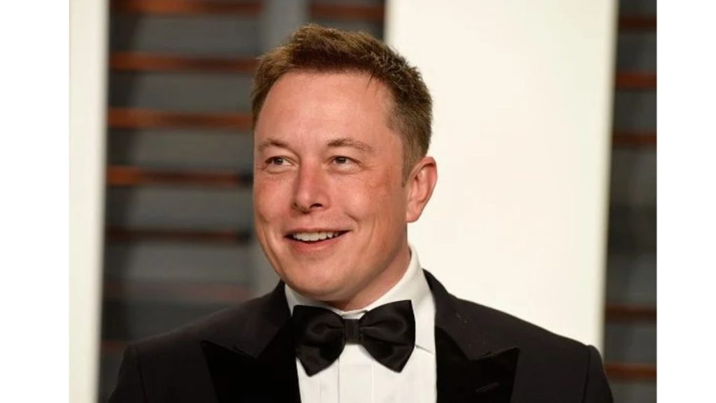 Elon Musk smiling in a black tuxedo at a formal event