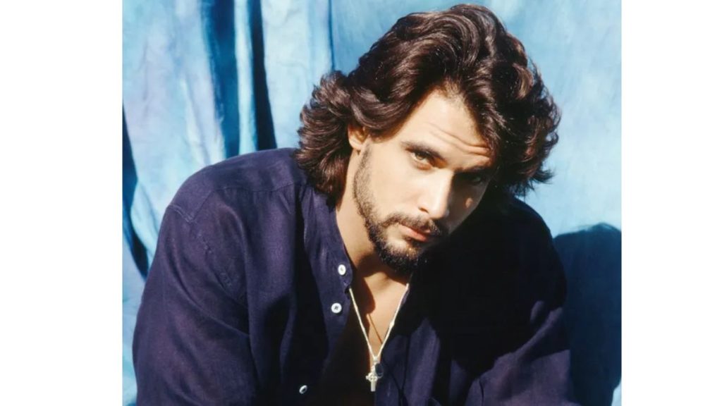 Robert Kelker Kelly wearing a dark jacket and looking down.